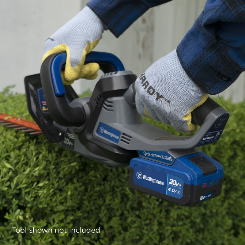 Closeup of 4 Ah battery in Westinghouse cordless hedge trimmer. Hedge trimmer being used on a bush