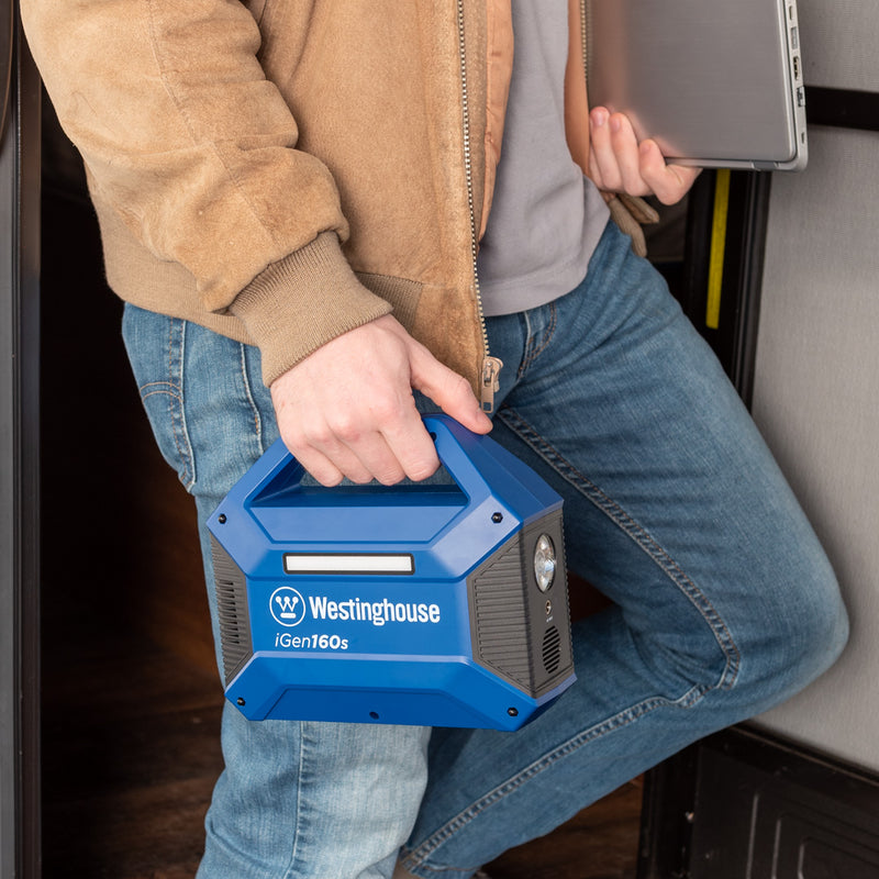 Westinghouse | iGen160s Portable Power Station and a laptop being carried by a man.