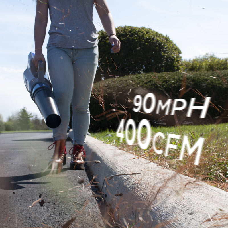 A woman walks towards the camera while using a leaf blower to blow debris off of the street. The text reads 