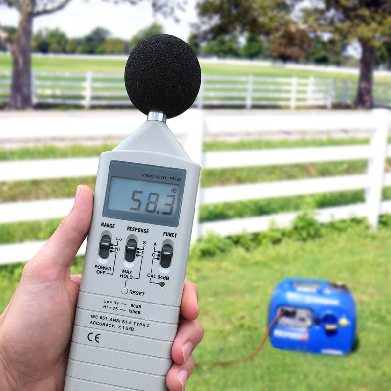 Westinghouse | WH2200iXLT inverter generator sitting on grass with a decibel meter measuring 58.3 decibels in the foreground.